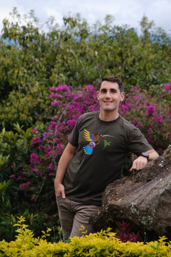 Portrait of Simon Erlich smiling warmly in front of soft purple flowers